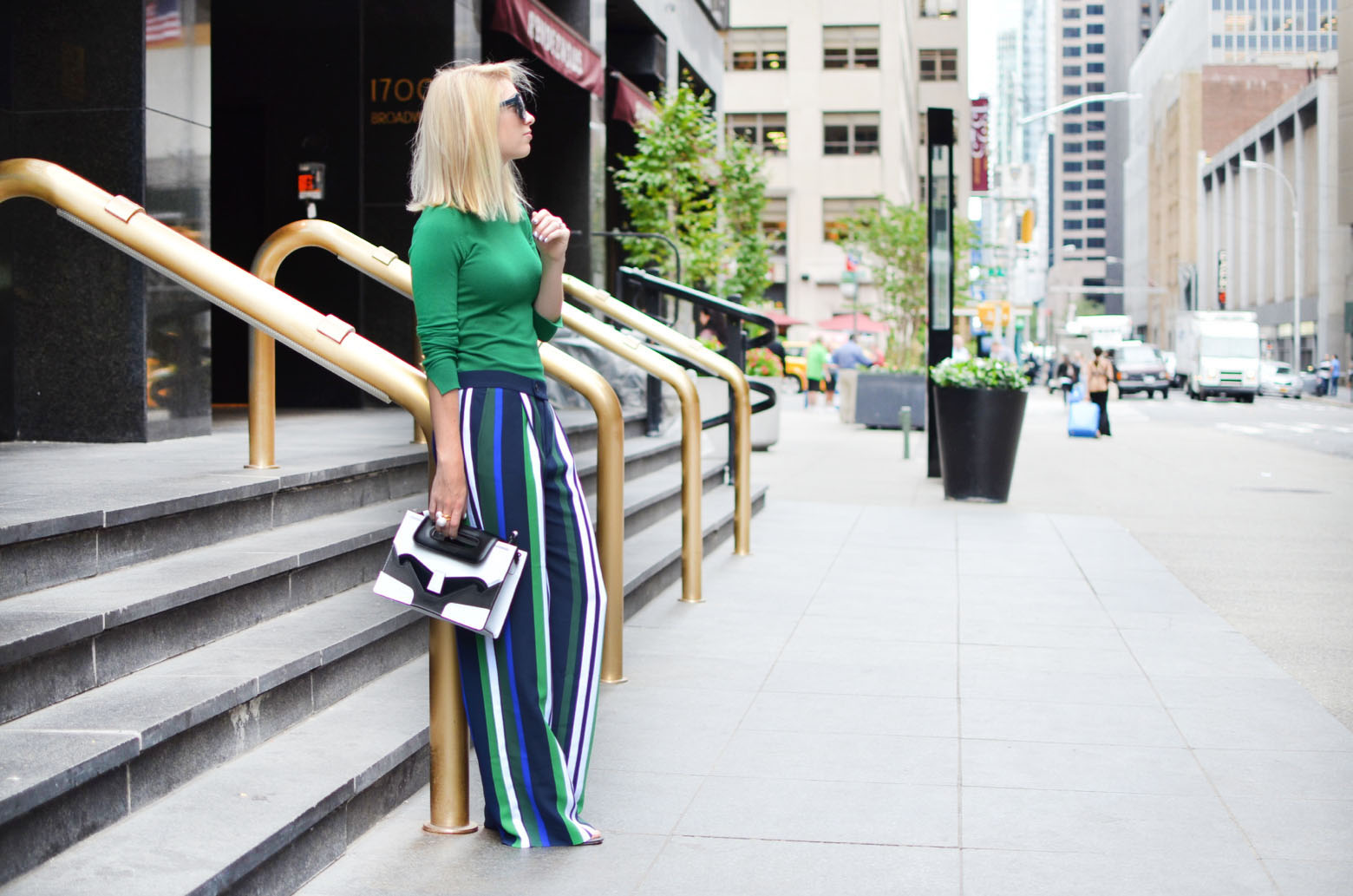 Stefanie from The Style Safari wears a green long sleeve sweater, vertical stripe wide leg pants, black and white graphic clutch // thestylesafari.com