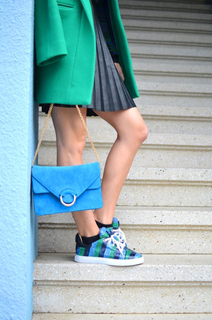 emerald green and bright blue outfit, kelly green coat, pleated faux leather black skirt, blue suede shoulder bag, snakeskin sneakers // thestylesafari.com