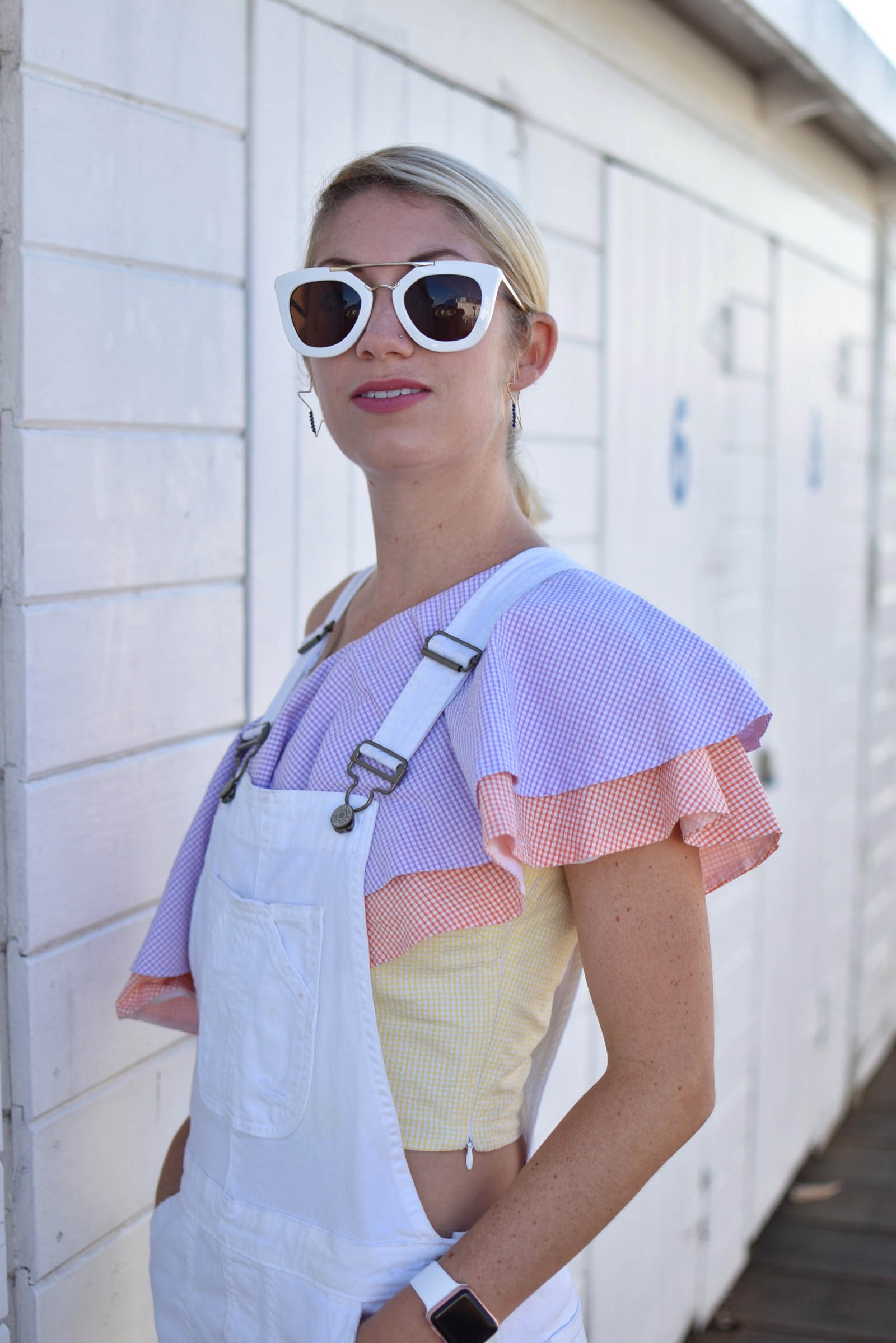 white modern overalls, styled with pastel ruffle top, white sunglasses