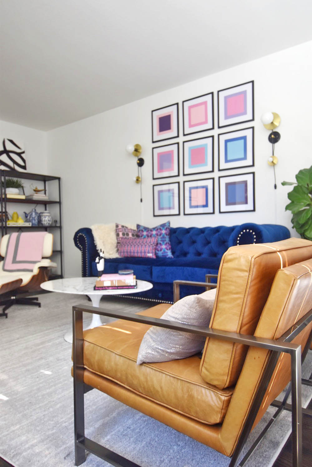 Midcentury glam living room, navy chesterfield sofa, saarinen tulip table, pop art, pink and blue, eames lounge chair, leather arm chair