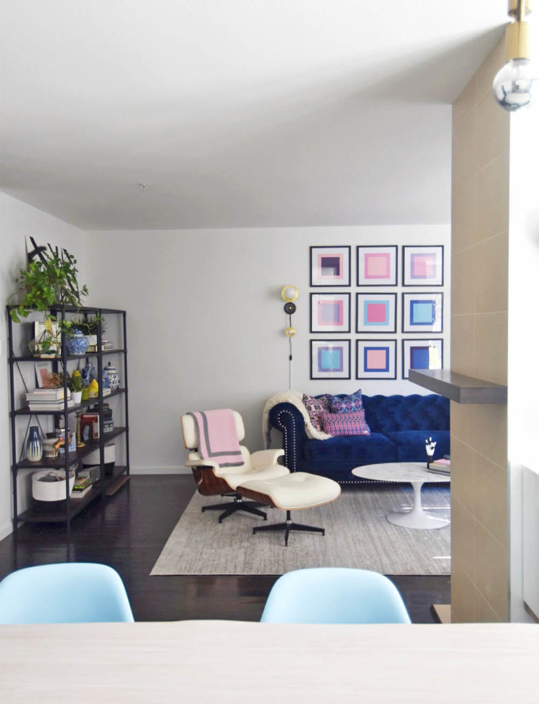 Midcentury glam living room, navy chesterfield sofa, saarinen tulip table, pop art, pink and blue, eames lounge chair